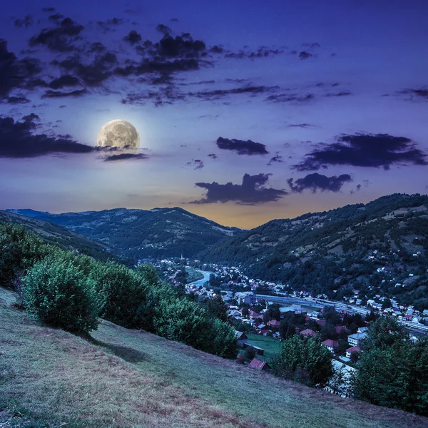 Desa di sisi bukit padang rumput dengan hutan di gunung di malam hari — Stok Foto