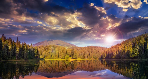 Pinède et lac près de la montagne tôt au coucher du soleil — Photo