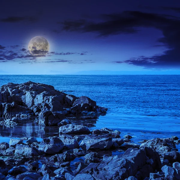 stock image sea wave breaks about  boulders at night