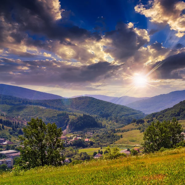 Dorp in voet bergdal met bos bij zonsondergang — Stockfoto