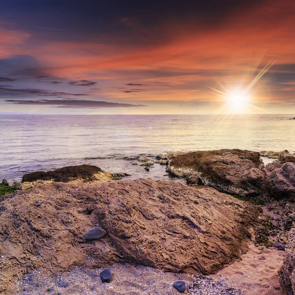 Sea wave breaks about boulders at sunset — Stock Photo, Image