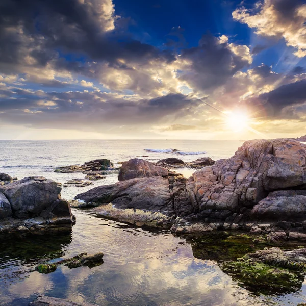 Sea wave breaks about boulders at sunset — Stock Photo, Image