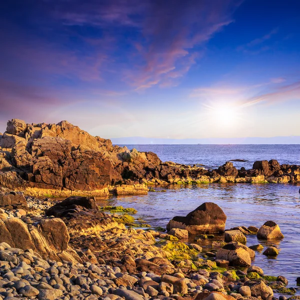 Sea wave breaks about boulders at sunset — Stock Photo, Image