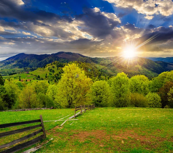 Fence on hillside meadow in mountain at sunset — Stock Photo, Image