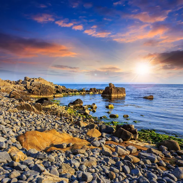 Sea wave breaks about boulders at sunset — Stock Photo, Image