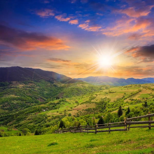 Fence on hillside meadow in mountain at sunset — Stock Photo, Image