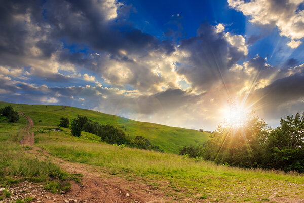 path on hillside meadow in mountain at sunset