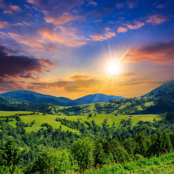 Villaggio su prato collinare con bosco in montagna al tramonto — Foto Stock