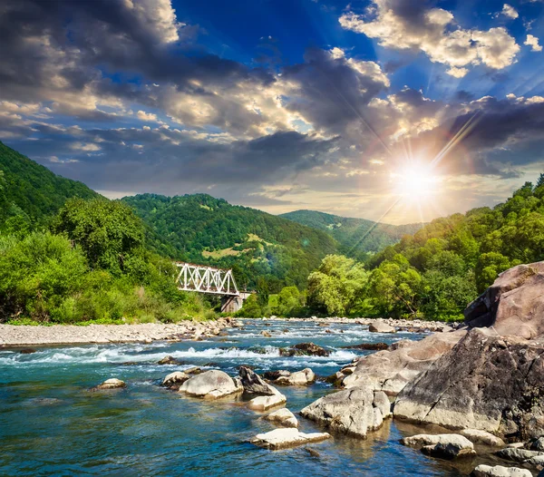 Rivière forestière avec pierres et pont au coucher du soleil — Photo