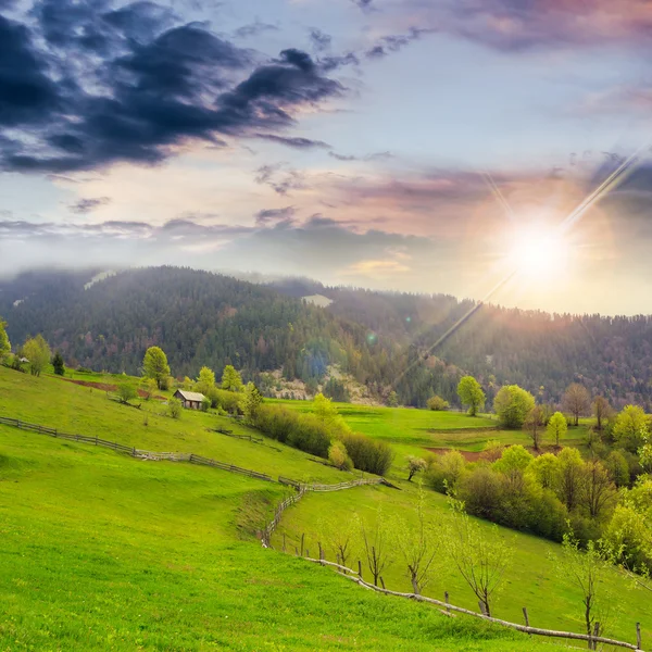 Fence on hillside meadow in mountain at sunset — Stock Photo, Image