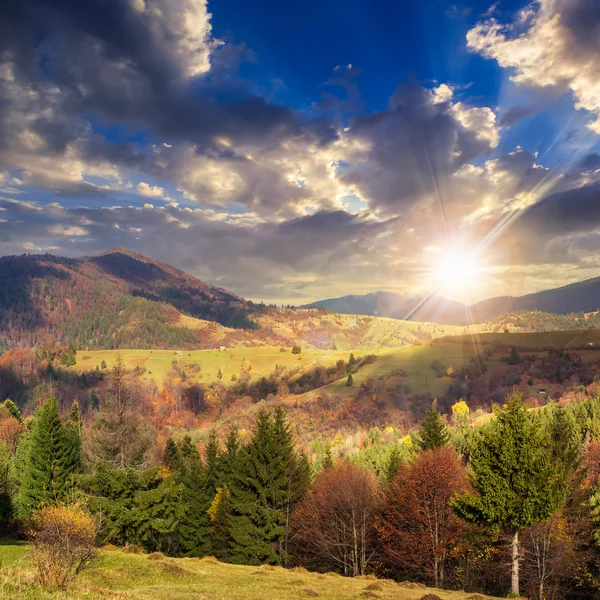 Byn på hillside äng med skog i berg vid solnedgången — Stockfoto