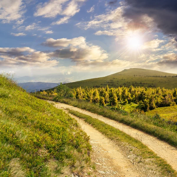 Road on a hillside near mountain peak at sunset — Stock Photo, Image