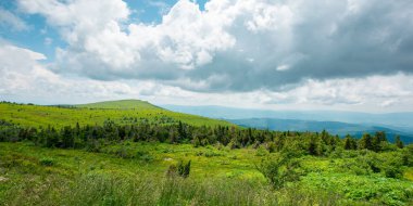 Öğle vakti cennet gibi dağ manzarası. Zirvenin üstündeki bulutlar ve güneşli bir günde tepeler. Yazın harika doğa manzarası