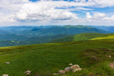 beautiful view of green mountain landscape. sunny outdoor nature scenery in summer. stones on the grassy hill. clouds above ridge on horizon in the distance