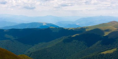 Dağlardaki güzel doğa manzarası. Güneşli bir günde Borzhava sırtı manzarası. Ormanlı tepeler. ve benekli ışıkta çimenli çayırlar. Ufkun üstündeki gökyüzünde bulutlar