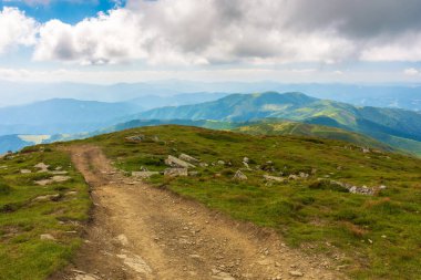 Carpathian Ulusal Parkı 'nın sırtından geçen yol. Ukrayna 'nın dağ manzarası, yazın Avrupa. Güzel bir açık hava manzarası. yerli turizm ve yürüyüş konsepti. Çimenli tepeler ve çayırlar güneşli bir günde