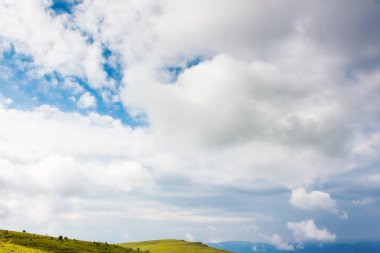 Yeşil tepeler ve çayırlar üzerindeki bulutlar. Güneşli bir günde dağ manzarası. Güzel yaz manzarası