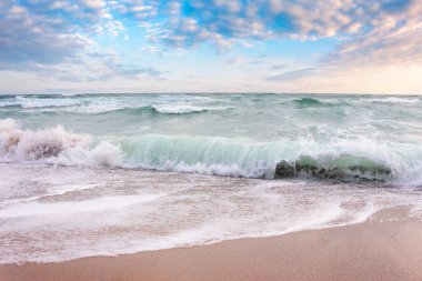 Güneş doğarken sahile vuran dalgalı deniz manzarası. Güzel yaz manzarası Denizde sabah ışığında