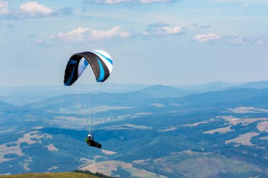 Dağ vadisinde yamaç paraşütü yapıyor. Açık hava sporları. macera ve seyahat konsepti. Yazın gökyüzünde bulutlar