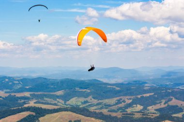 Dağ vadisinde yamaç paraşütü yapıyor. Açık hava sporları. macera ve seyahat konsepti. Yazın gökyüzünde bulutlar