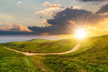 Yazın gün batımında Karpatlar 'ın dağ manzarası. Toprak yol ve yürüyüş yolu. Akşam ışığında tepelik bir kırsal alanın panoramik görüntüsü. tatil ve aktif yaşam tarzı kavramı