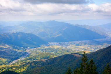 Güneşli bir sonbahar sabahında dağ manzarası. Uzak vadideki köy. Orman tepesinden bir manzara
