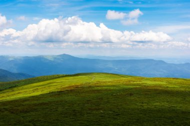 Benekli ışıkta yeşil manzara. Güneşli bir günde Karpat Dağları 'nın çimenli çayırları. Gökyüzü ufukta bulutlarla