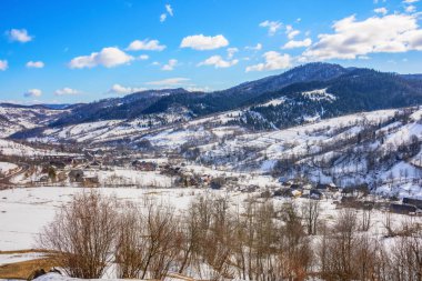 Kışın kırsal karpatlar vadisi. Güneşli bir günde köyle birlikte harika bir dağ manzarası. Tepelerde karla kaplı tarlalar