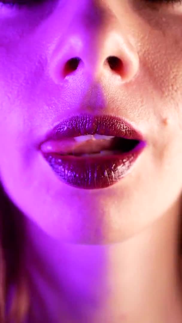 Mulher sexy lambe os lábios. Luz brilhante de néon. Extremo close-up. Conceito de vida noturna — Vídeo de Stock