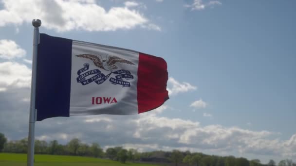 Bandeira de Iowa em um mastro de bandeira acenando no vento no céu. Estado de Iowa nos Estados Unidos da América — Vídeo de Stock