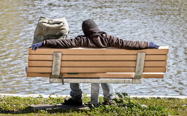 человек спит на скамейке в парке
