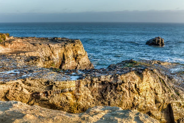 Solbelysta stenar på naturliga broar state beach — Stockfoto