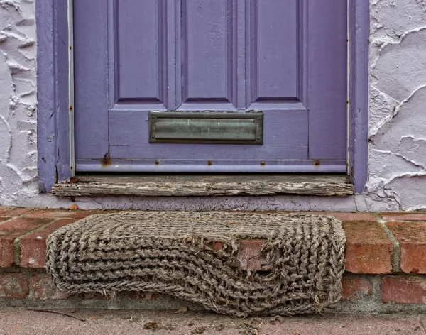 Fialové dveře s opotřebovanou koberec — Stock fotografie