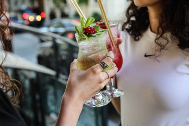 Uzun martini bardaklarında iki porsiyon çikolatalı tatlı. İki genç kadın ellerinde tatlı bardaklarıyla restoranın arka planında bulanık, seçici bir odak noktası var. Şerefe, arkadaşlarla boş zaman..