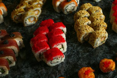 Siyah bir arka planda yansımalı geleneksel lezzetli suşi rulosu. Pilavlı suşi, kırmızı balık, somon balığı. Suşi menüsü. Japon mutfağı, restoran. Deniz ürünleri, Asya yemekleri.