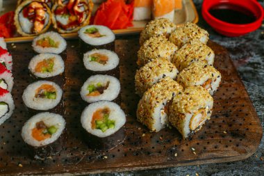 Siyah bir arka planda yansımalı geleneksel lezzetli suşi rulosu. Pilavlı suşi, kırmızı balık, somon balığı. Suşi menüsü. Japon mutfağı, restoran. Deniz ürünleri, Asya yemekleri.