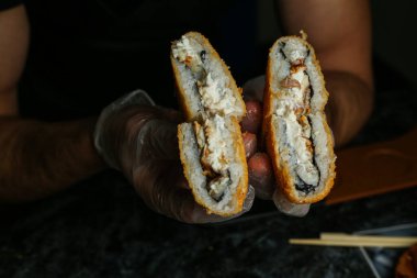 Siyah bir arka planda yansımalı geleneksel lezzetli suşi rulosu. Pilavlı suşi, kırmızı balık, somon balığı. Suşi menüsü. Japon mutfağı, restoran. Deniz ürünleri, Asya yemekleri.