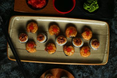 Siyah bir arka planda yansımalı geleneksel lezzetli suşi rulosu. Pilavlı suşi, kırmızı balık, somon balığı. Suşi menüsü. Japon mutfağı, restoran. Deniz ürünleri, Asya yemekleri.