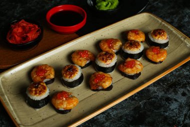 Siyah bir arka planda yansımalı geleneksel lezzetli suşi rulosu. Pilavlı suşi, kırmızı balık, somon balığı. Suşi menüsü. Japon mutfağı, restoran. Deniz ürünleri, Asya yemekleri.