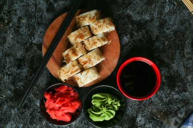 Siyah bir arka planda yansımalı geleneksel lezzetli suşi rulosu. Pilavlı suşi, kırmızı balık, somon balığı. Suşi menüsü. Japon mutfağı, restoran. Deniz ürünleri, Asya yemekleri.