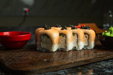 Siyah bir arka planda yansımalı geleneksel lezzetli suşi rulosu. Pilavlı suşi, kırmızı balık, somon balığı. Suşi menüsü. Japon mutfağı, restoran. Deniz ürünleri, Asya yemekleri.