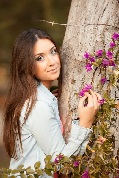 Unga vackra kvinnan luktar blommor — Stockfoto