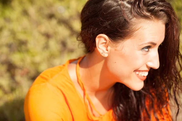 Portrait of young beautiful woman laughing wearing orange shirt — Stock Photo, Image