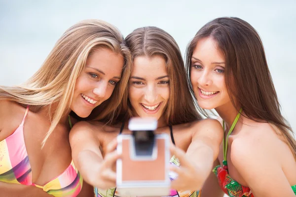 Three young beautiful girlfriends having fun on the beach with a — Stock Photo, Image