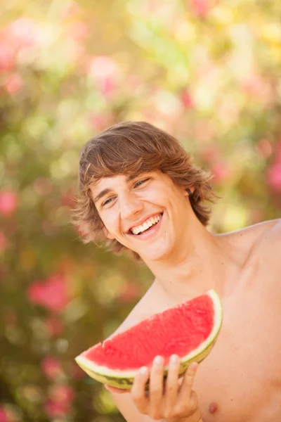 Portrait of a beautiful young man eating watermelon — Stock Photo, Image