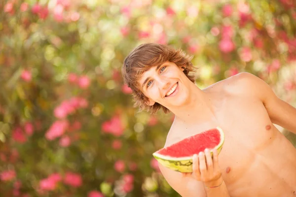 Retrato de um belo jovem comendo melancia — Fotografia de Stock