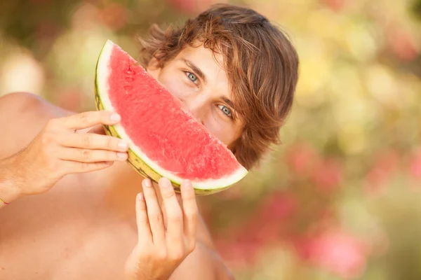 Retrato de um belo jovem comendo melancia — Fotografia de Stock