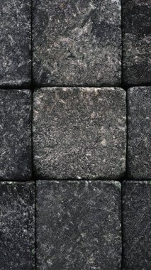 Taş cep telefonu duvar kağıdı. Doğal dokular. Siyah arkaplana yakın koyu gri. Pürüzlü bir yüzey, kayalardan oluşmuş pürüzlü bir yapı. İşlemden kaynaklanan çizikler ve izler var. Dikey arkaplan