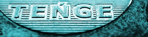 Yazının çevirisi: tenge. Bir Kazak sikkesinin 100 onluk parçası. Ulusal para biriminin Latince yakın plan adı. Kazakistan 'da ekonomi veya iş hakkında turkuaz renkli pankart