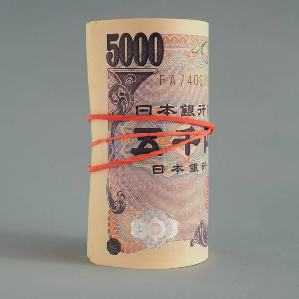 近くには5 000円の日本円札の束があります 濃い灰色の背景 銀行券はロールアップされ 弾性バンドで結ばれています 正方形のイラスト 銀行への預金またはローン マクロ — ストック写真